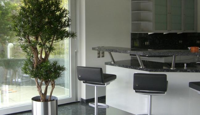 Massgefertigter Premium Kunstbaum in einem edelstahl Topf, der in einer Küche steht.