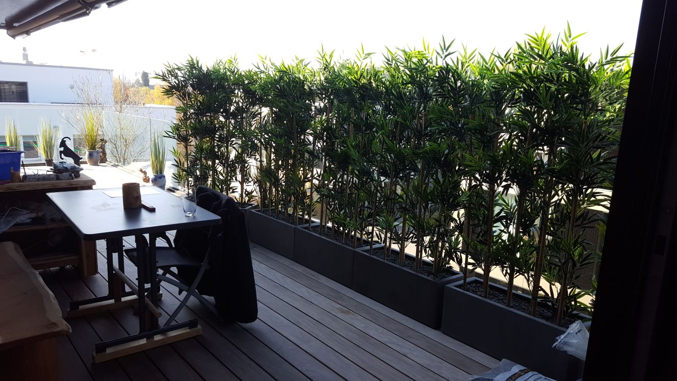 Moderne Terrassengestaltung mit künstlichen Bambus Hecken im Kübel.